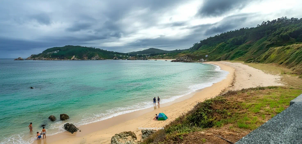 Quiet curved bay in Espasante on the northern Spain coastline with turquoise water, sandy beach, and green hills.