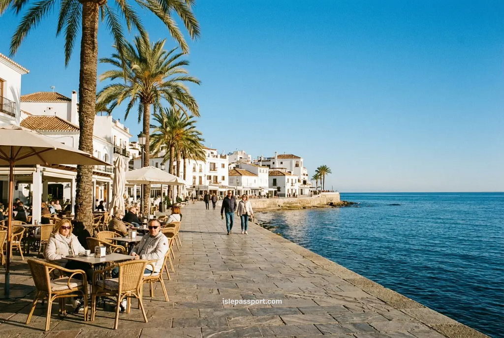 A bright, sunny beach promenade in Southern Spain during winter, lined with palm trees and busy outdoor cafés under a clear blue sky.