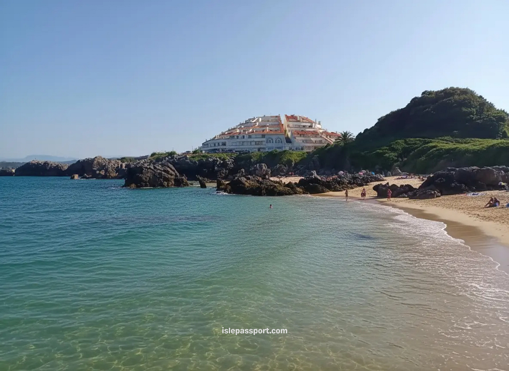 Small sandy cove in Bárcena de Cicero on the northern Spain coastline with turquoise water, rocky edges, and a few swimmers.