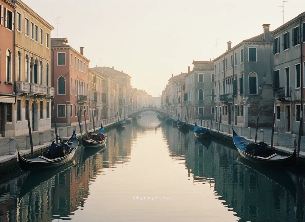 Quiet Venice canal at sunrise with gondolas and pastel buildings.