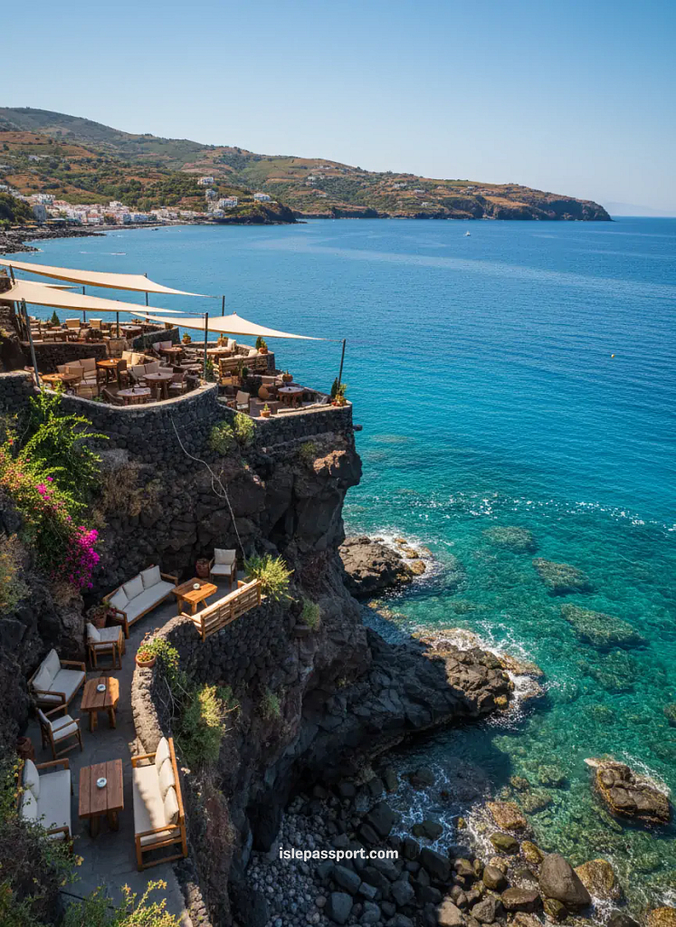 Cliffside café in Lipari built above turquoise water with rugged volcanic rock and coastal towns across the bay