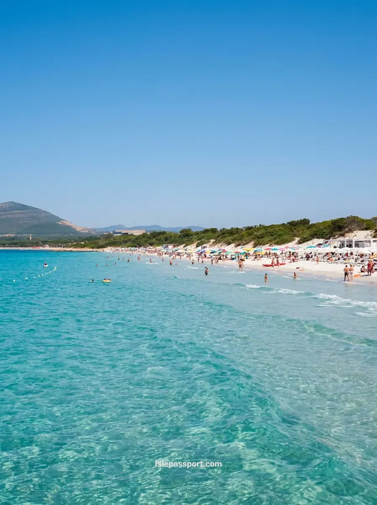 Long sandy beach at Spiaggia di Maria Pia near Alghero Sardinia with turquoise water and colourful umbrellas on the shore