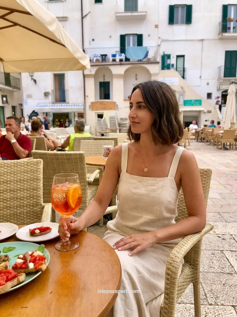 A woman enjoying an Aperol Spritz and fresh bruschetta at a sun-drenched outdoor cafe in Sperlonga, Italy.