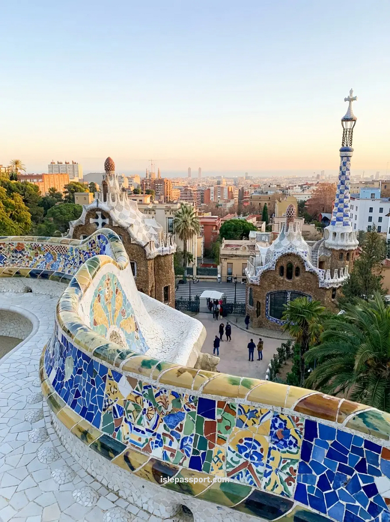 Barcelona Park Güell Gaudí mosaic bench and pavilions in winter with Sagrada Familia visible in city skyline