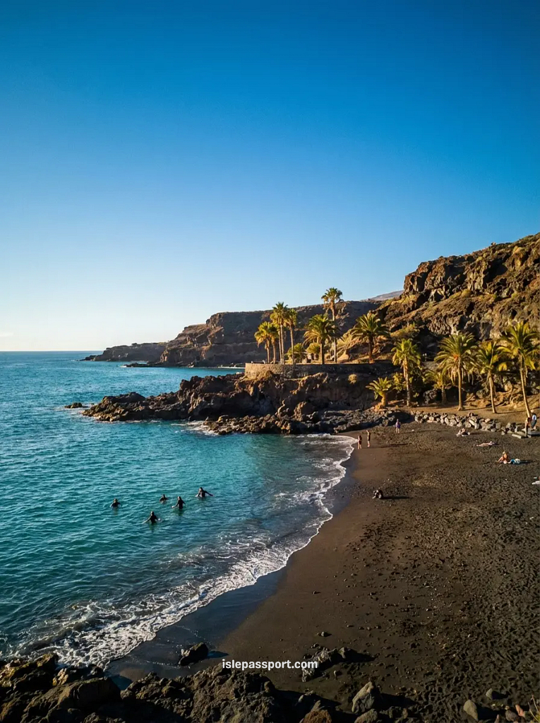 Volcanic black sand beach in Tenerife in winter with people swimming in January. Tenerife is one of the Best Places to Visit In Spain In Winter