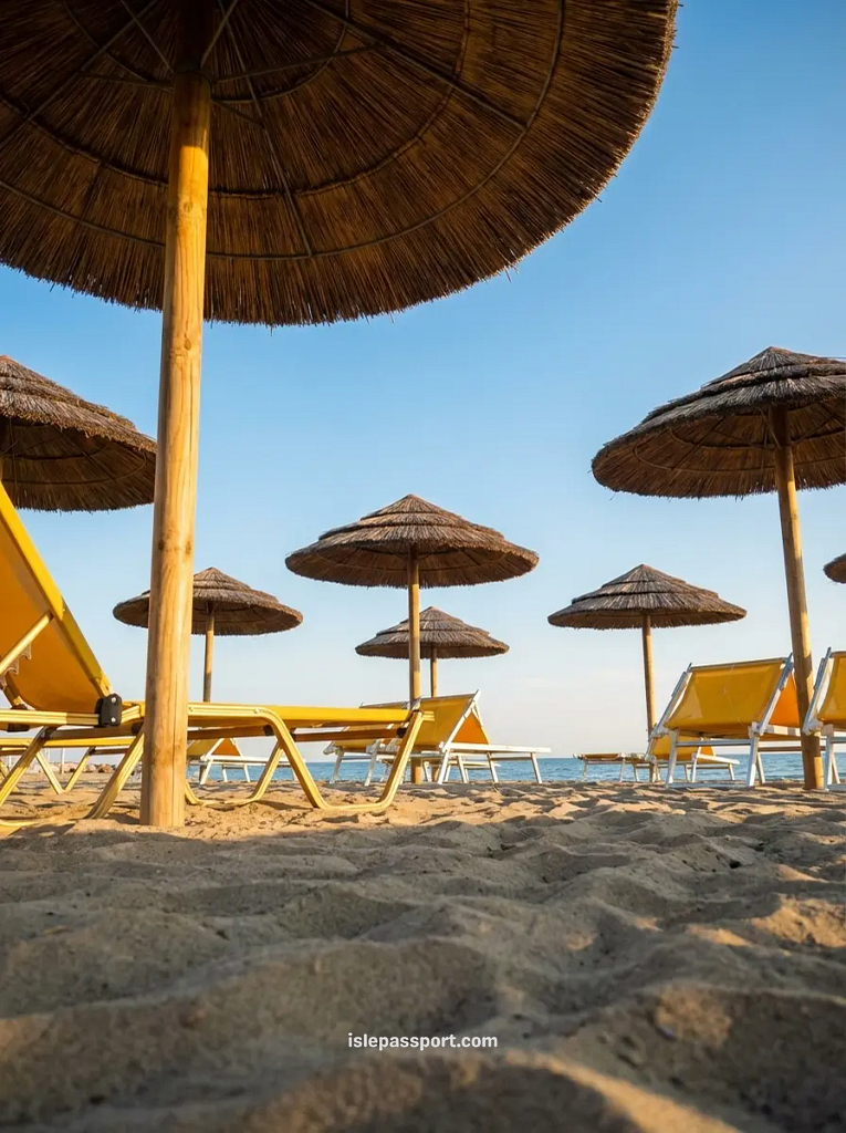 Golden sandy beach in Calambrone, Italy, featuring straw umbrellas and yellow lounge chairs facing the sea