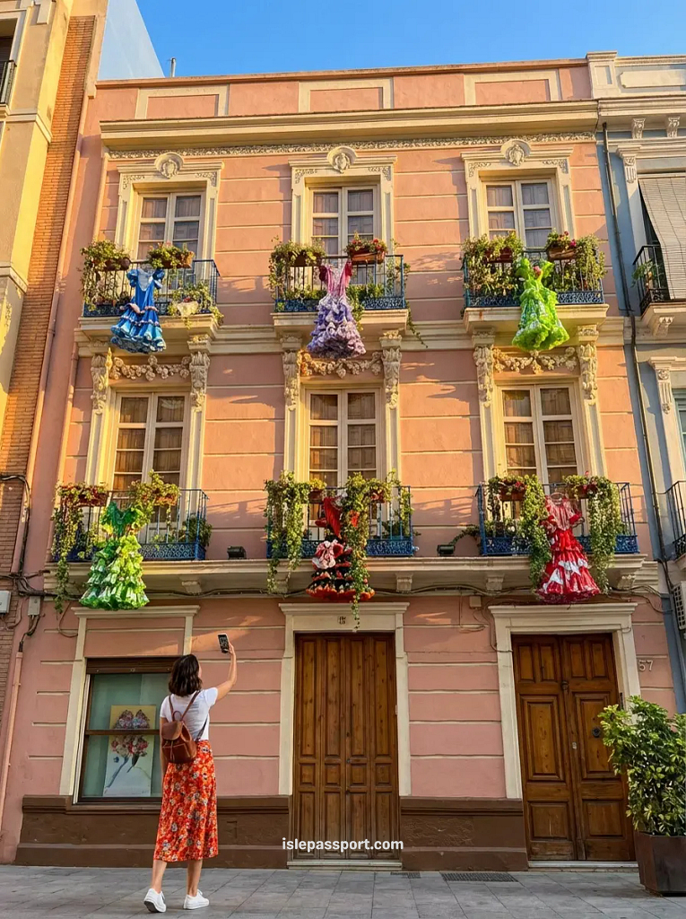 Traditional Málaga building in El Perchel neighbourhood decorated with colourful flamenco dresses on iron balconies