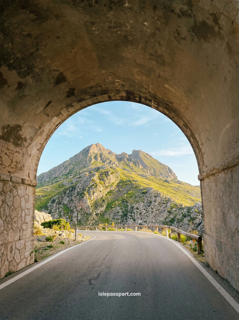 A narrow paved road passing between two massive, vertical limestone cliffs on the Sa Calobra road during a Mallorca coastal road trip in the Serra de Tramuntana.