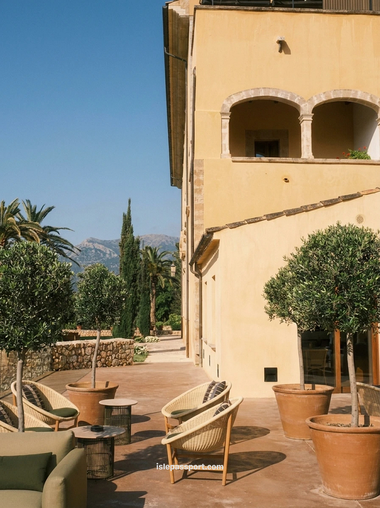 Terrace seating area with potted olive trees outside an 18th-century monastery building at Son Brull, a boutique hotel near Pollença, Mallorca, with the Tramuntana mountains in the background