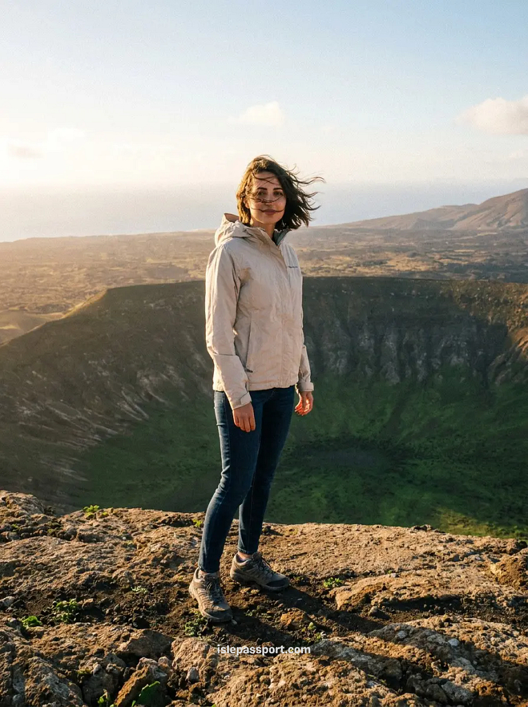 Hiker in a windproof jacket at the Caldera Blanca crater rim in Lanzarote in winter, green crater floor below