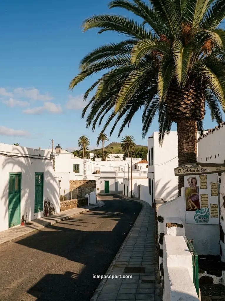 Quiet street in Haría, Lanzarote, with white houses, green doors and tall palm trees