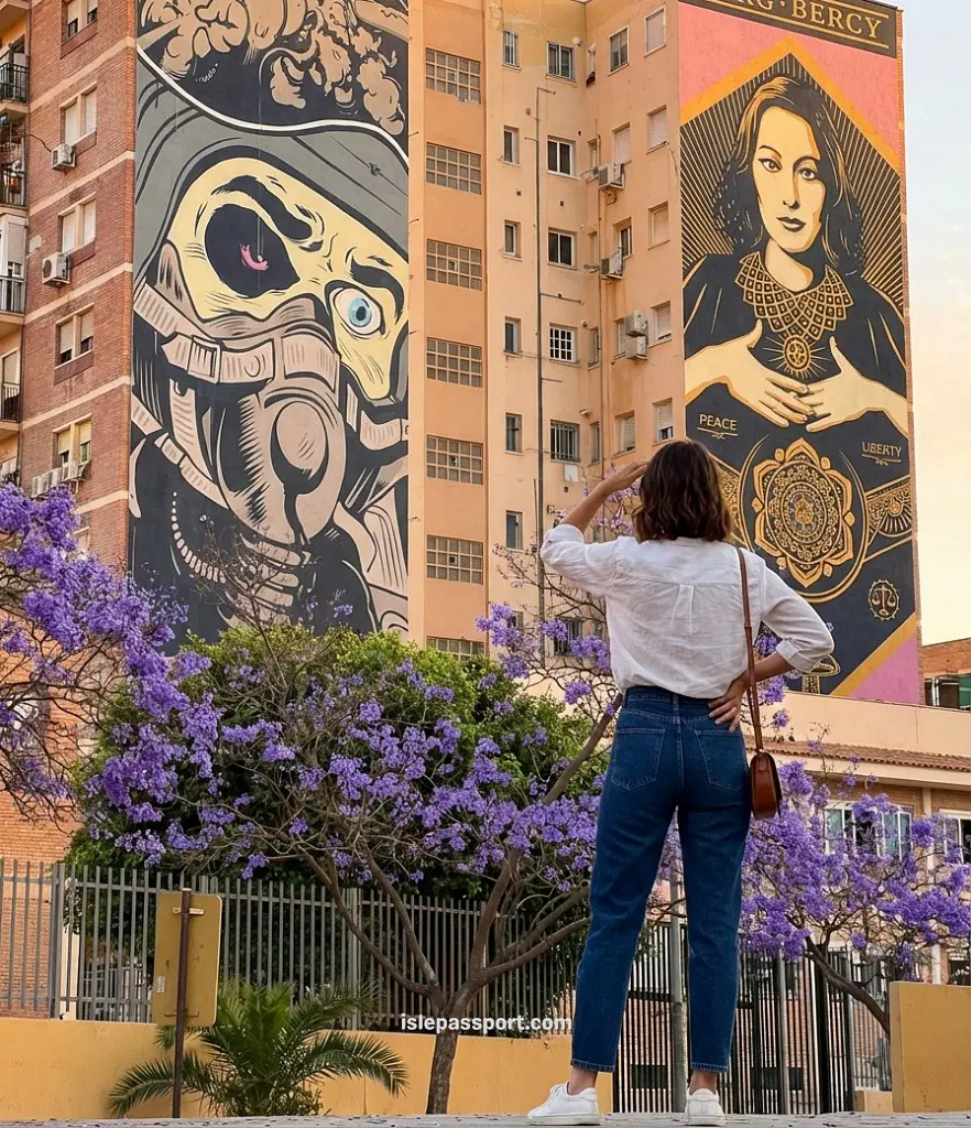 Giant street art murals in Málaga's Soho arts district with flowering jacaranda trees in the foreground